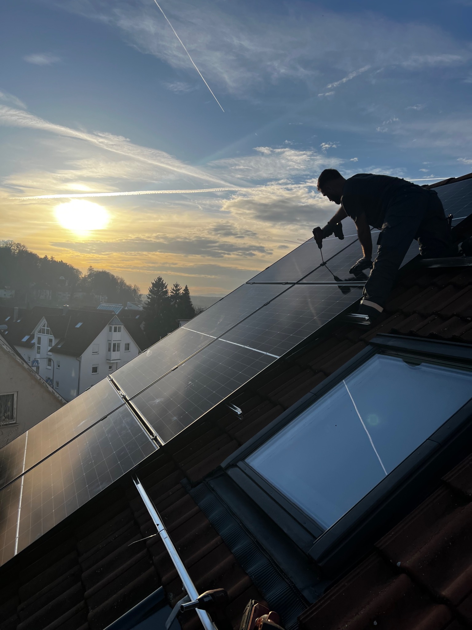 Monteur von BH PV-Montage bei der Installation von Solarmodulen auf einem Dach im Abendlicht